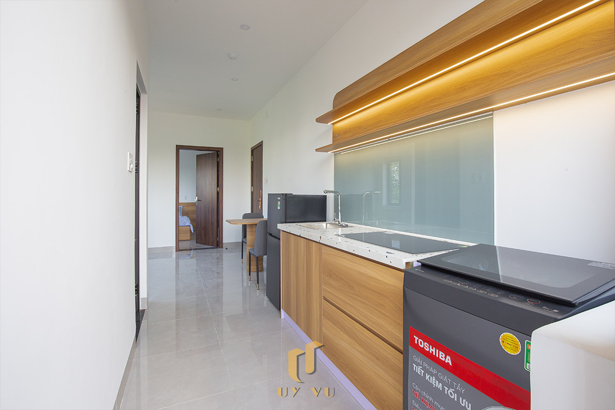 Mỡ Apartment – Căn Hộ Cho Thuê Đà Nẵng Hiện Đại, Tối Ưu 19-Khu bếp căn hộ Mỡ Apartment với tủ gỗ, bếp điện và thiết bị giặt tích hợp